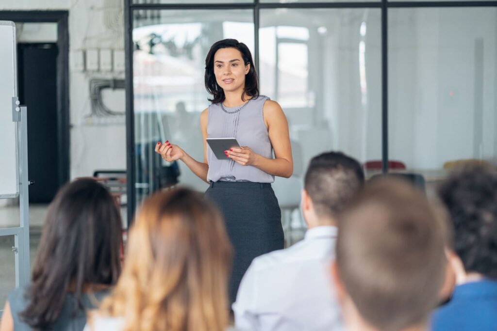 a woman standing in front of an audience talking