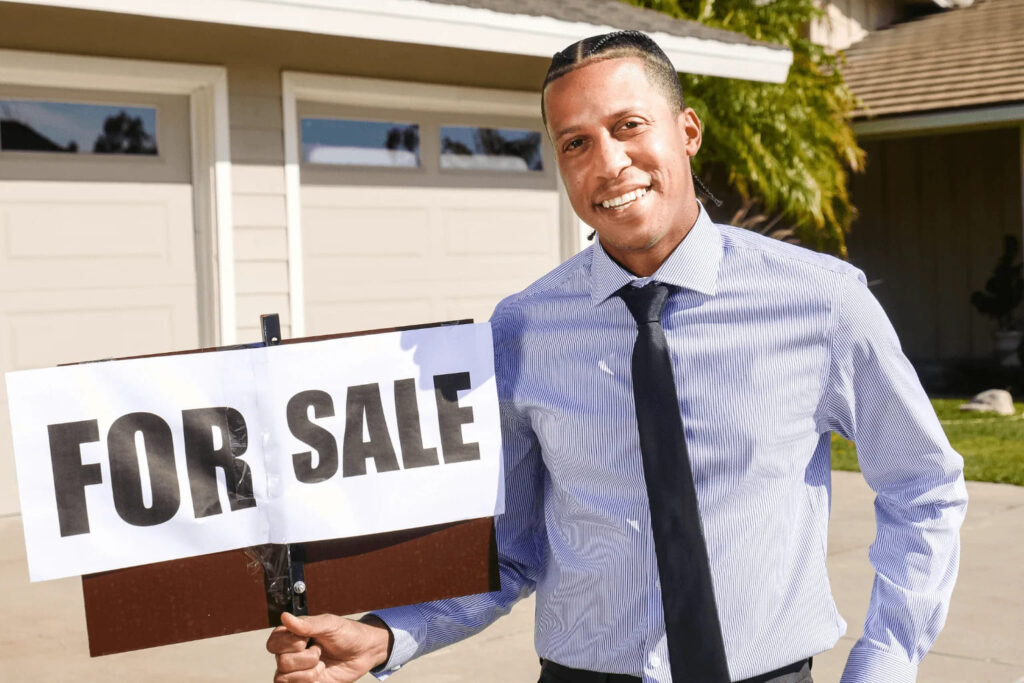 Realtor putting up a for sale sign in front of a house