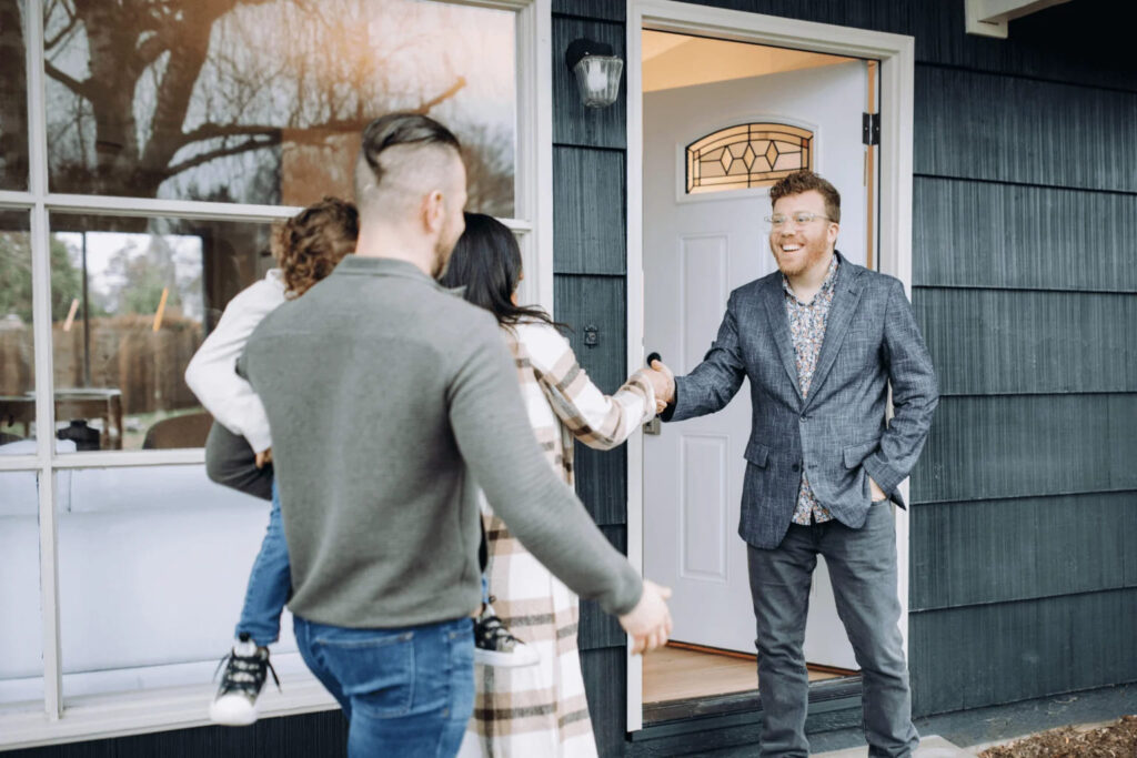 Real estate agent guiding first-time buyers in front of a home